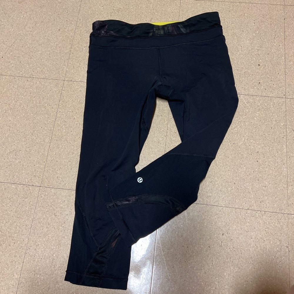 Black lululemon leggings with a subtle floral design and neon green detailing